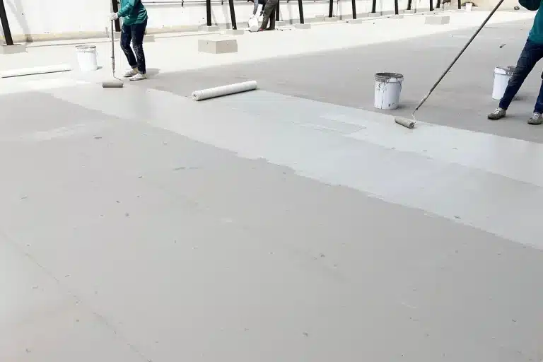 roofers rolling a white coat on a commercial building
