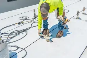 a man in a yellow long-sleeved shirt working on a commercial roof