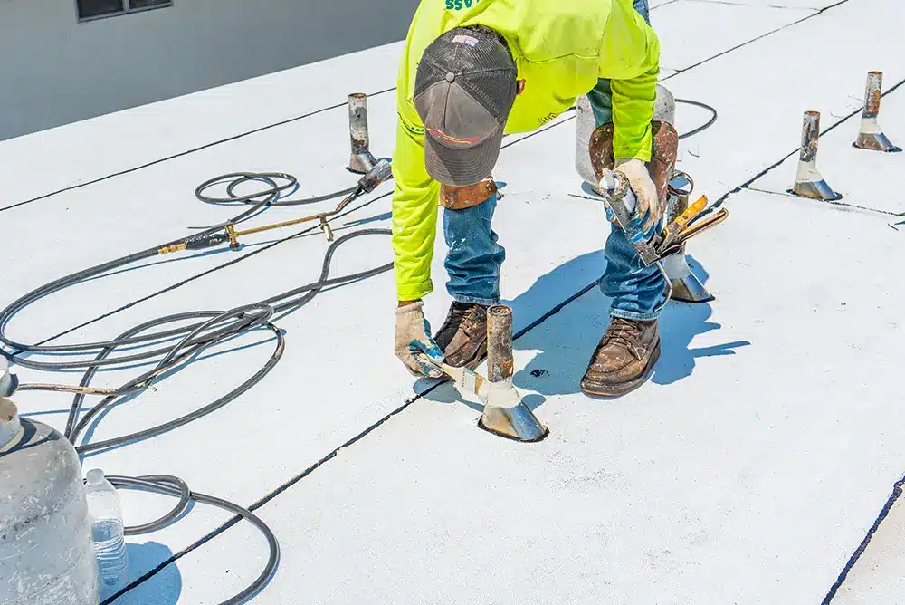 a man in a yellow long-sleeved shirt working on a commercial roof