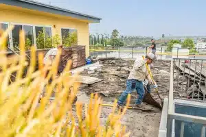 a worker pushing a wheelbarrow while working on a roof