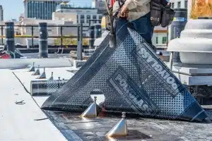 a man laying down new roofing material