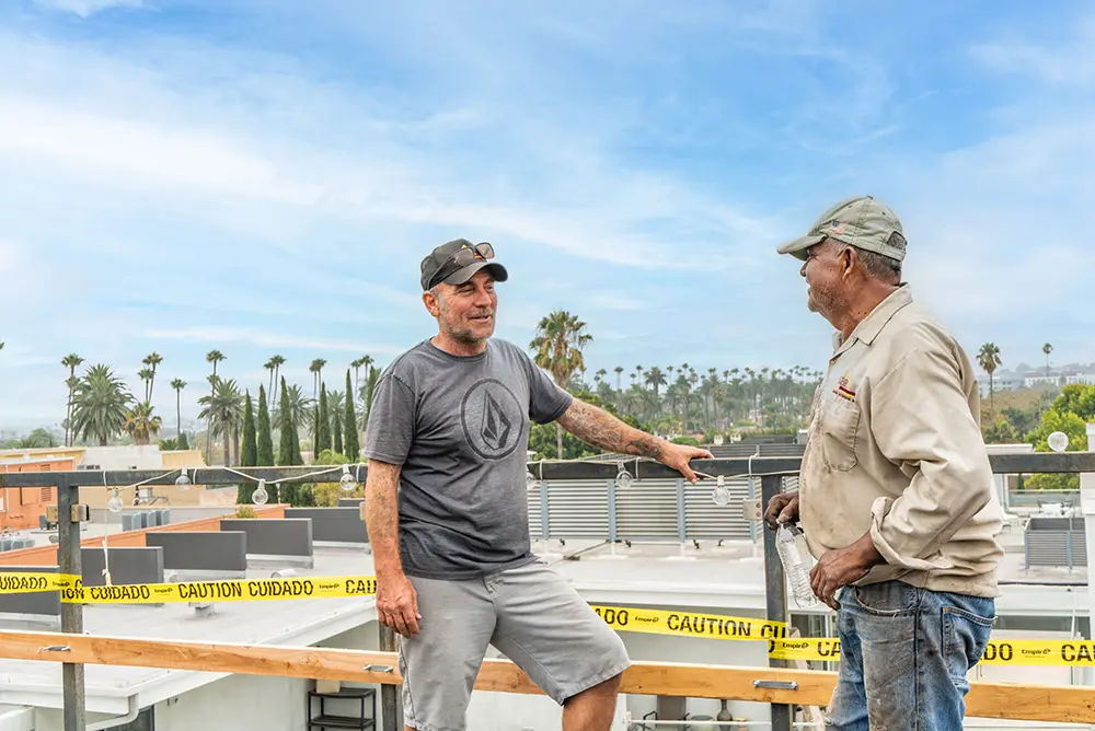 two men standing on a commercial building roof talking