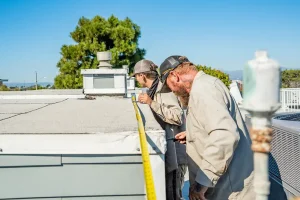 Three workers repairing a roof.