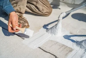 A roofing contractor putting down preventative coating to prevent roof leaks