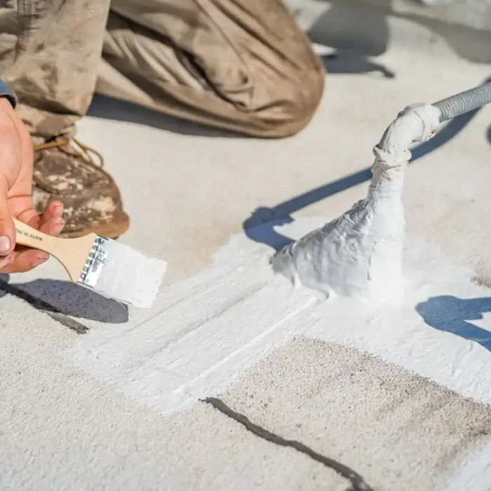 A roofing contractor putting down preventative coating to prevent roof leaks