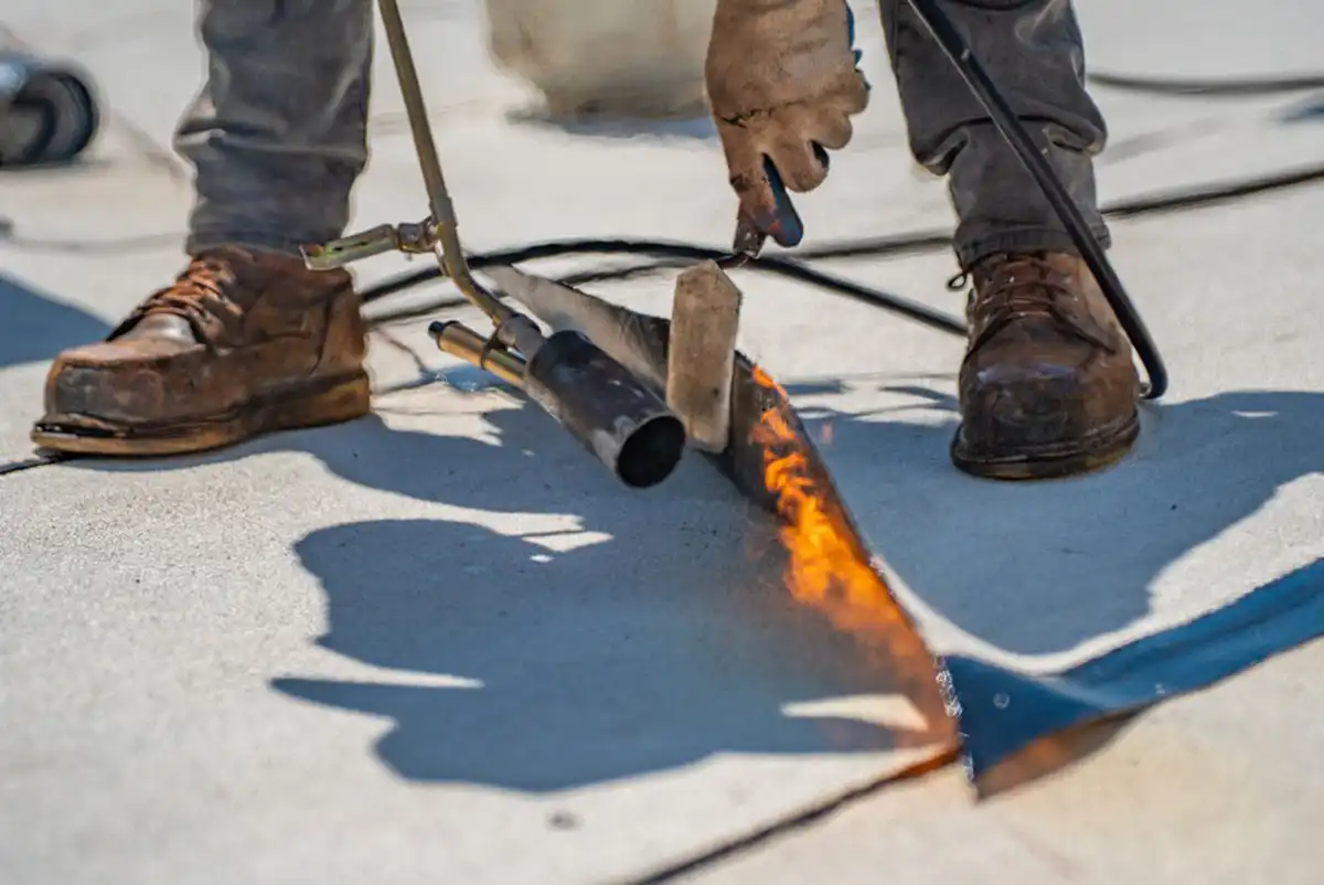 a commercial roofing contractor using a blowtorch on a roofing tile